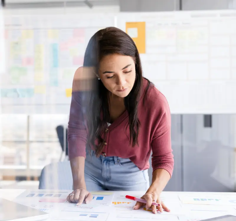 Woman analyzing printed charts on a table in a modern office.